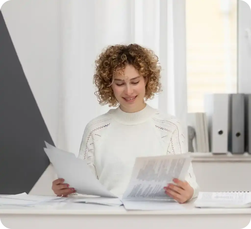 Vrouw die documenten bekijkt in een moderne kantooromgeving, wat staat voor professioneel beheer en analyse.